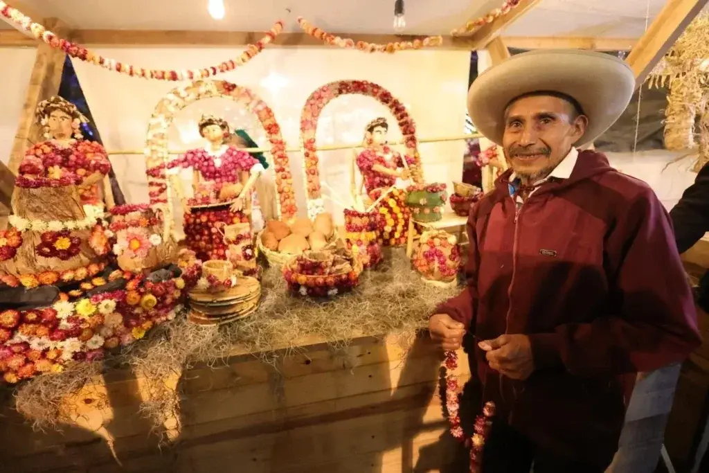 Artisan poses beside a totomoxtle and flower work at the Night of Radishes. Photo: Qué Onda Oaxaca Artisan poses beside a totomoxtle and flower work at the Night of Radishes. Photo: Qué Onda Oaxaca